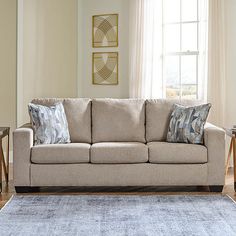 a living room scene with focus on the couch and rug in front of the window