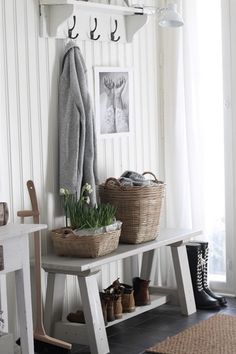 a coat rack with two baskets on top of it next to some shoes and plants