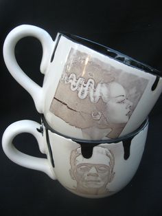 two coffee mugs with pictures on them sitting side by side in front of a black background