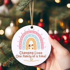 someone holding up a christmas ornament that says changing lives one family at a time