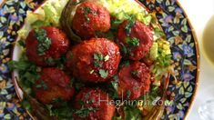 meatballs with lettuce and tomato sauce on a colorful plate next to a glass of wine