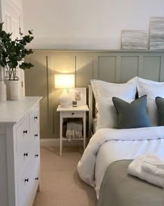 a bed room with a neatly made bed next to a night stand