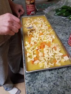 the man is preparing his meal on the counter with noodles and carrots in it