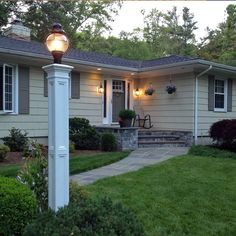 a house with a lamp post in front of it and landscaping around the porch area