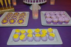 purple and yellow desserts on white plates with candles in the background at a party