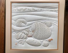 an art work with shells and seashells on white paper, framed in wooden frame