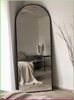 a large mirror sitting in the corner of a room next to a bed and table