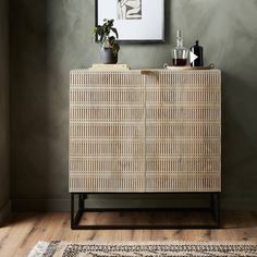 a wicker cabinet with bottles on top and a rug in the corner next to it