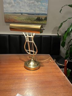 a desk lamp sitting on top of a wooden table next to a potted plant