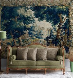 a green couch sitting in front of a wall with a tapestry hanging on it's side