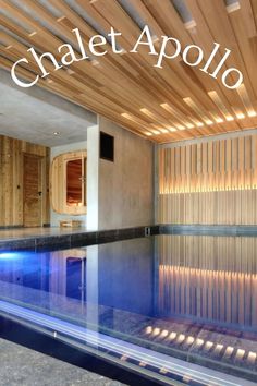 an indoor swimming pool surrounded by wooden slats and lights with the words chalet apollo above it