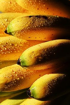 several bananas with water droplets on them sitting in a pile next to eachother