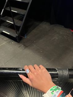 a woman's hand on the handle of a metal object in front of stairs