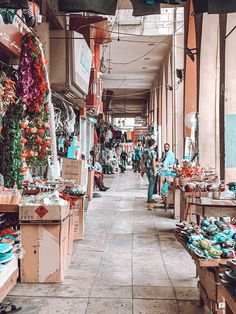 an outdoor market with lots of items for sale and people walking through the store area