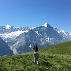 a woman standing on top of a lush green hillside