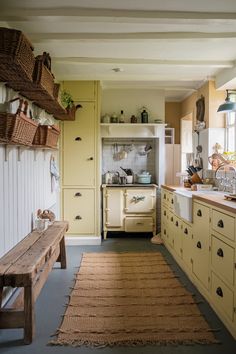 an old fashioned kitchen with yellow cabinets and rugs on the floor in front of the stove