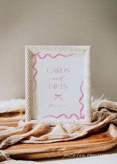 a card and gifts sign sitting on top of a wooden tray next to a blanket