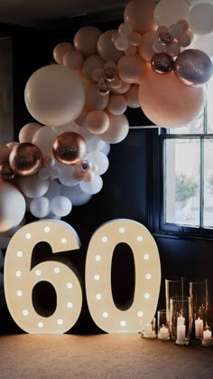 balloons and candles are arranged around the number 60 sign