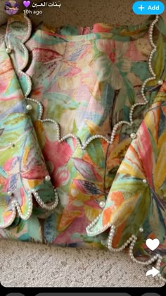 an image of a purse with pearls on the bottom and flowers on the inside, sitting on carpet