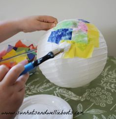 someone is painting a paper lantern on a table