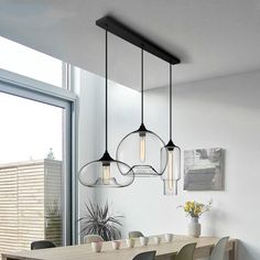 a dining room table with chairs and lights hanging from it's ceiling over it