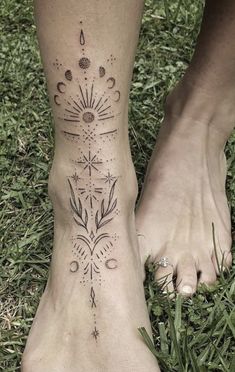 a woman's foot with tattoos on it and grass in front of her feet