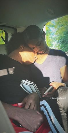 two people sitting in the back seat of a car looking at their cell phones