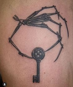 a skeleton holding a key tattoo on the back of a man's shoulder with barbed wire around it