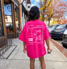 a woman in a pink shirt is walking down the sidewalk with her hand on her hip