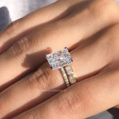 a woman's hand with an engagement ring and two wedding bands on her finger