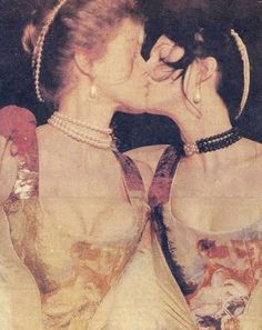 two women are kissing each other while wearing pearls and necklaces on their necklines