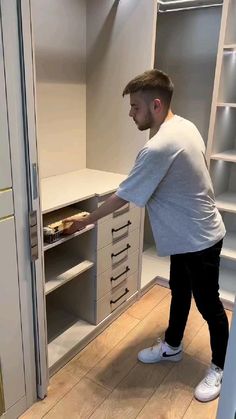 a man is holding an ironing board in his hand while standing next to some cabinets