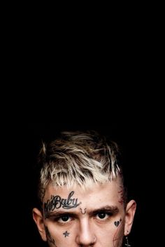 a man with tattoos and piercings on his face is looking at the camera while standing in front of a black background