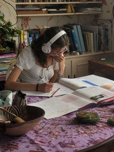 a woman sitting at a table in front of an open book with headphones on