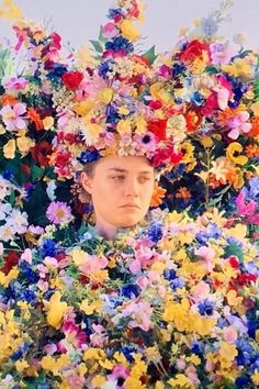 a woman with flowers on her head in the middle of a large group of flowers