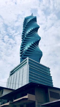 a tall building with a spiral design on it's side and sky in the background