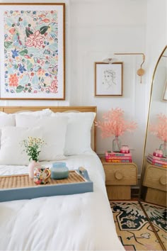 a bed with white sheets and pillows in a bedroom next to a large painting on the wall