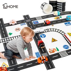 a baby is playing with cars and trucks on the playmat that looks like a race track