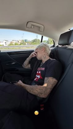 a man sitting in the back seat of a car talking on a cell phone while holding his hand up to his ear