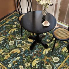 a black table with two chairs and a vase filled with flowers on top of it