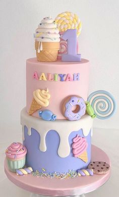 a pink and blue birthday cake with donuts, ice cream, lollipops, pretzels and more