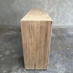 a large wooden block sitting on top of a cement floor next to a concrete wall