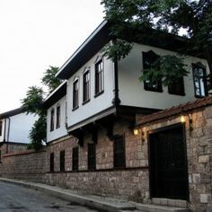 the building is made of stone and has black shutters on both sides, along with windows