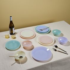 a table topped with plates and bowls next to a bottle