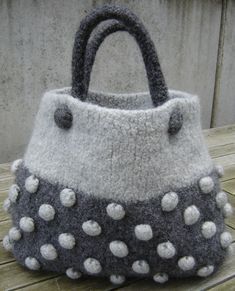 a gray and white purse sitting on top of a wooden table