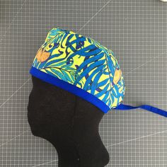 a hat with blue and yellow designs on it sitting on top of a mannequin's head