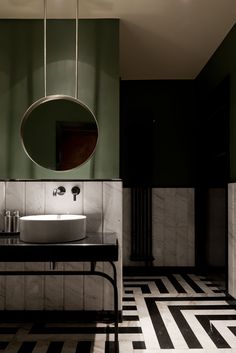 a black and white tiled bathroom with a round mirror above the sink, along with two circular mirrors on the wall