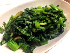 a white bowl filled with green vegetables on top of a table