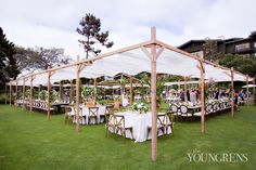 a large tent with tables and chairs set up for an outdoor wedding reception in the grass