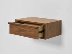 a wooden drawer with two drawers on the front and one in the back, hanging from a white wall